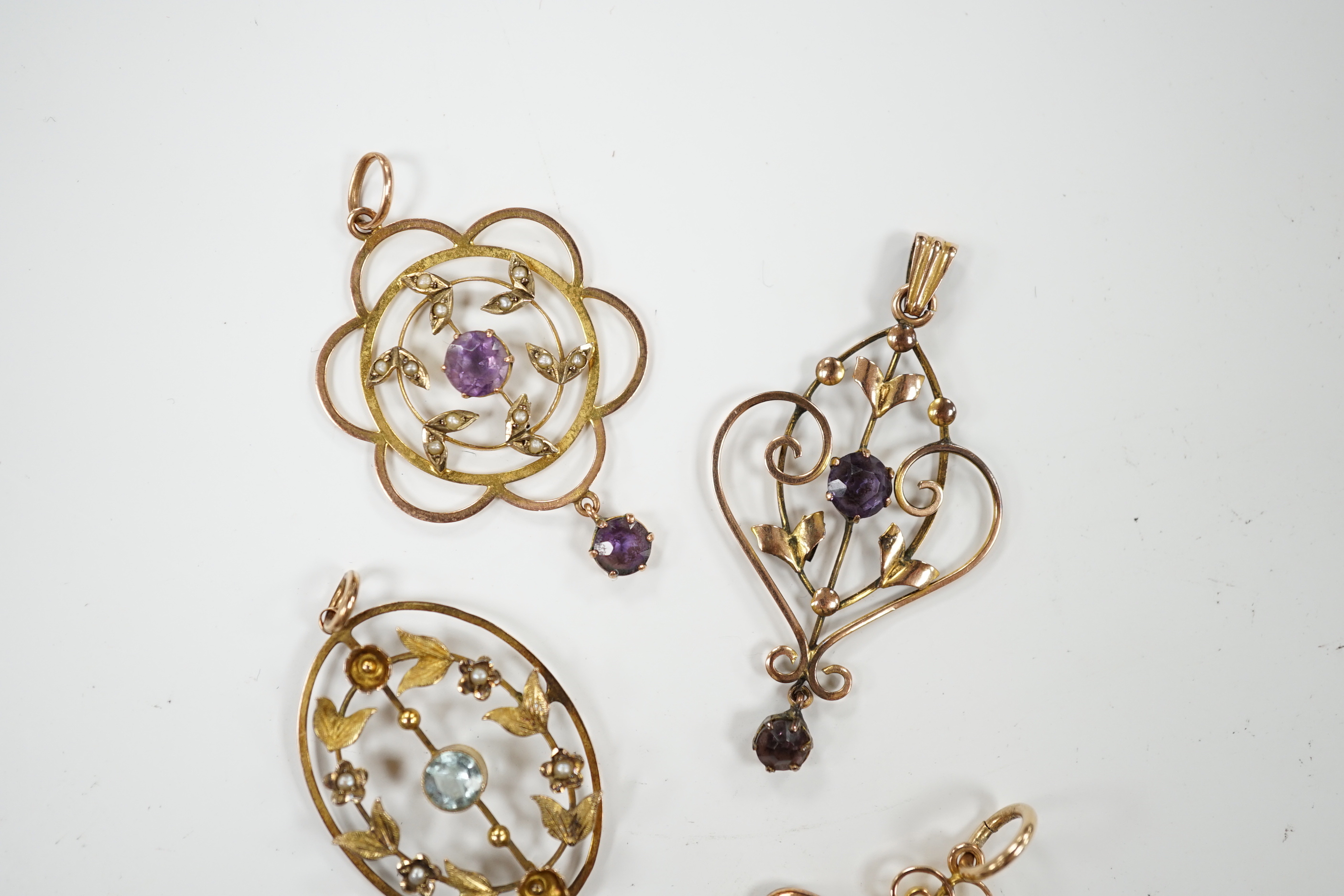 Three assorted early 20th century 9ct and gem set pendants, one other similar yellow metal and gem set pendant, largest, 40mm, gross weight 7.5 grams.